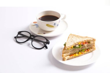 Beyaz arka planda bir fincan kahveli ızgara sandviç..