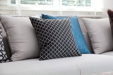 Mavi ve siyah desenli yastıklar evdeki beyaz koltukta..