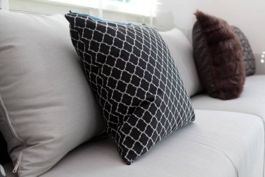 Mavi ve siyah desenli yastıklar evdeki beyaz koltukta..