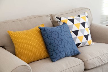 Pastel, mavi ve sarı yastıklar beyaz bir kanepede, oturma odasının iç tarafında..