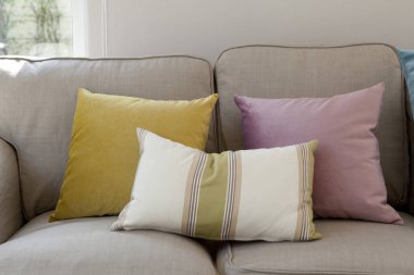 Pastel, mavi ve sarı yastıklar beyaz bir kanepede, oturma odasının iç tarafında..