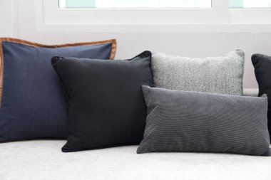 Mavi ve siyah yastıklı, komodinin üzerinde siyah okuma lambası olan modern tarz iç yatak odası..