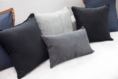 Mavi ve siyah yastıklı, komodinin üzerinde siyah okuma lambası olan modern tarz iç yatak odası..