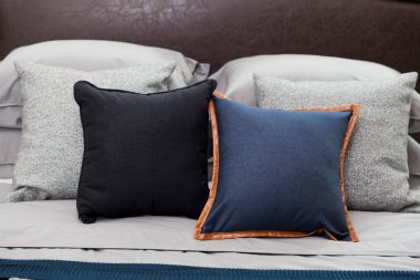 Mavi ve siyah yastıklı, komodinin üzerinde siyah okuma lambası olan modern tarz iç yatak odası..