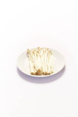 Enoki mantarı, beyaz arka planda altın iğneli mantar.