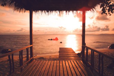 Kumsalda hafta sonu tatili. Günbatımında, tropik plajın yanındaki ahşap çardak..