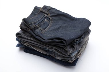 Beyaz arka planda katlanmış mavi kot pantolon yığını.