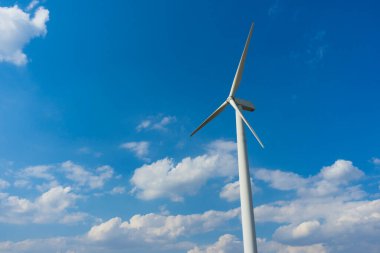Yeşil yenilenebilir alternatif enerji kavramı, rüzgar jeneratörü türbini mavi gökyüzü ile elektrik üretiyor.