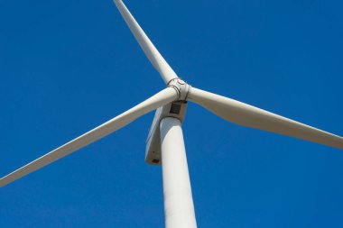 Yeşil yenilenebilir alternatif enerji kavramı, rüzgar jeneratörü türbini mavi gökyüzü ile elektrik üretiyor.