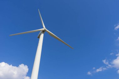 Yeşil yenilenebilir alternatif enerji kavramı, rüzgar jeneratörü türbini mavi gökyüzü ile elektrik üretiyor.