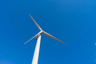 Yeşil yenilenebilir alternatif enerji kavramı, rüzgar jeneratörü türbini mavi gökyüzü ile elektrik üretiyor.