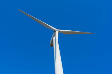 Yeşil yenilenebilir alternatif enerji kavramı, rüzgar jeneratörü türbini mavi gökyüzü ile elektrik üretiyor.