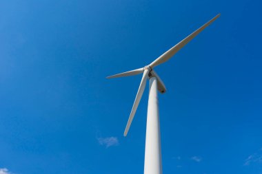 Yeşil yenilenebilir alternatif enerji kavramı, rüzgar jeneratörü türbini mavi gökyüzü ile elektrik üretiyor.