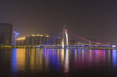 Guangzhou şehir manzarası Pearl Nehri üzerinde yükseliyor ve Liede Köprüsü geceleri Çin 'in Guangzhou şehrinde aydınlanıyor.