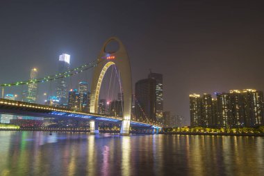 Guangzhou şehir manzarası Pearl Nehri üzerinde yükseliyor ve Liede Köprüsü geceleri Çin 'in Guangzhou şehrinde aydınlanıyor.