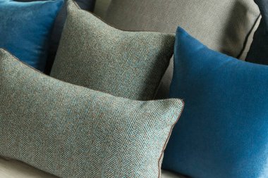 Yatağında gri ve mavi yastıklar olan şık bir yatak odası, rahat iç tasarım, modern iç mimari.