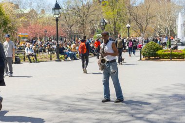 New York City, New York - 26 Nisan 2018: Kimliği belirsiz adam güneşli bir bahar gününde 26 Nisan 2018 'de ABD' nin New York şehrindeki Washington Square Park 'ta saksafon çalıyor.