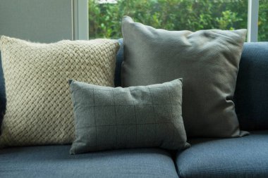 Mavi, beyaz ve gri yastıklar modern evdeki oturma odasında, mavi koltukta..