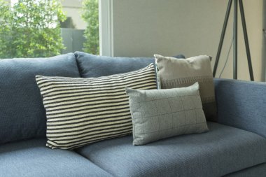 Mavi, beyaz ve gri yastıklar modern evdeki oturma odasında, mavi koltukta..