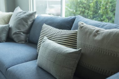 Mavi, beyaz ve gri yastıklar modern evdeki oturma odasında, mavi koltukta..