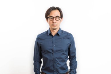 Orta yaşlı, siyah gömlekli ve gözlüklü bir Asyalı beyaz arka planda kameraya bakıyor.