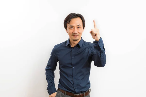 中年アジアの男で黒シャツで指差しとカメラを見ます上の白い背景 — ストック写真