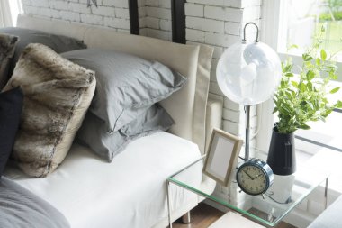 Modern lamba, resim çerçevesi ve saat yatağın yanındaki masada.