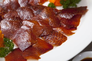 Pekin ördeği ya da ızgara ördek derisi taze sebze, tatlı sos ve buğdaylı Çin gözlemesi ile servis edilir..