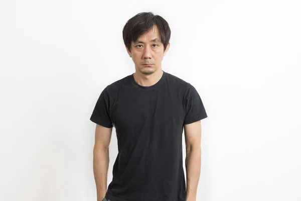 ハンサムな中年アジアの男でカジュアル黒Tシャツ見ますカメラで隔離された上の白い背景 — ストック写真