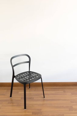 Beyaz bir odanın içindeki siyah metal sandalye.