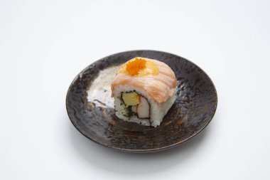 Somonlu suşi rulosu ve beyaz arka planda avokado.