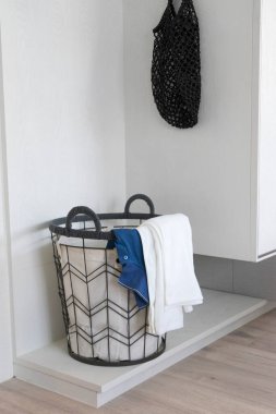 Kirli çamaşırlarla dolu çamaşır sepeti beyaz bir odanın köşesinde..