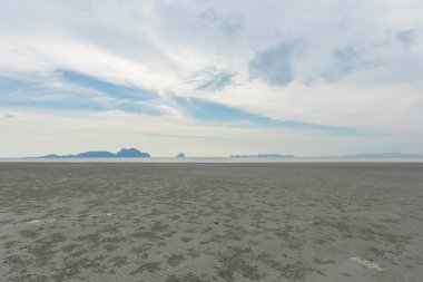 Ufukta ve denizde bulutlar olan pitoresk kumlu sahil