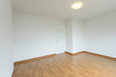 Beyaz duvarları ve tahta zemini olan boş bir oda..