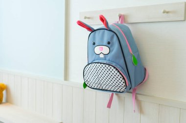 Mavi okul çantası çocuk odasında duvarda asılı..