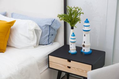 Battaniyeli ve yastıklı rahat bir yatak, masanın üstünde dekor.