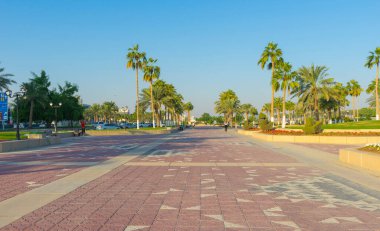 Doha, Katar - 23 Kasım 2019: Katar 'ın Doha kentinde Cornish Walk Way Park' ta mavi gökyüzü ile koşan kimliği belirsiz kişiler 