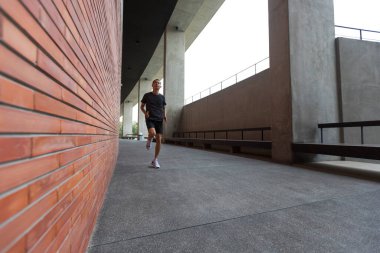 Etkin adam modern binanın duvarı boyunca çalışan spor giyim