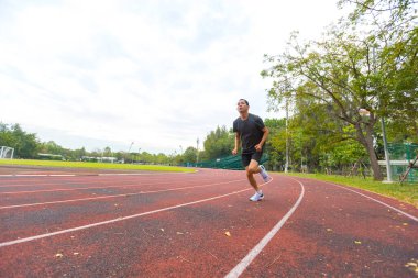 Koşu pistinde koşan ve antrenman yapan Asyalı genç adam.
