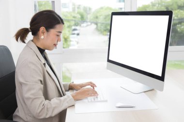 Olgun Asyalı kadın ofiste çalışıyor ve bilgisayar ekranına bakıyor..