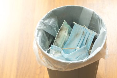 Medical face mask in the blue bin is full of trash. single use face mask. Right way to throwing used face mask in bin. 