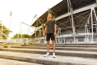 Genç atlet Asyalı adam stadyumun önünde koşuyor. Adam dışarıda antrenman yapıyor. Maratona hazırlanıyorum..