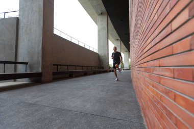 Etkin adam modern binanın duvarı boyunca çalışan spor giyim