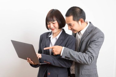 Resmi takım elbiseli Asyalı iş adamları dizüstü bilgisayarla birlikte çalışıp beyin fırtınası yapıyorlar. Beyaz arka planda duruyorlar..