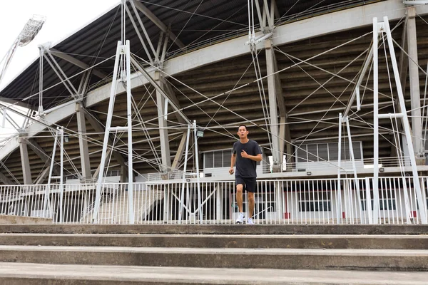 スタジアムの前を走る若いアスリートのアジア人男性 男は屋外で訓練する マラソンの準備 — ストック写真