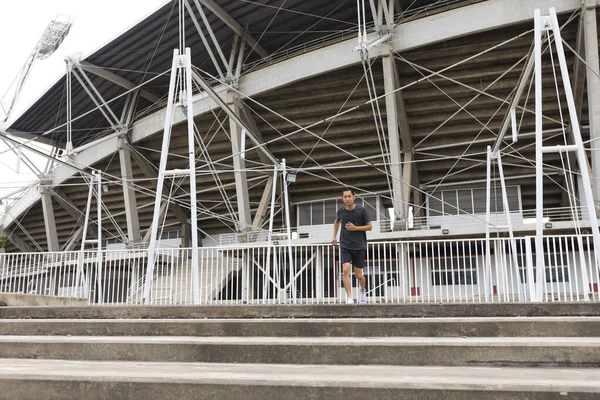 年轻的运动员亚洲男子跑在体育场前面 那个人在户外训练 筹备马拉松赛 — 图库照片