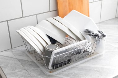 Yeni yıkanmış bulaşıklar, tabaklar, bardaklar, kavanozlar, bardaklar, çatal bıçak takımı, kurumayı bekleyen tavalar. Ev halkı kavramı ve günlük hayatta yardımcılar.