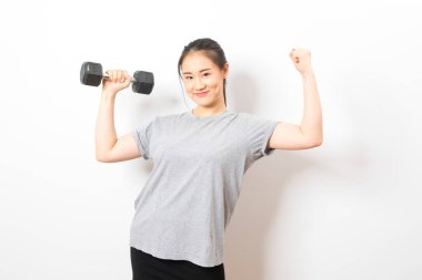 Asyalı kadın halterleri kaldırıyor ve bisepsi beyaz arka planda duruyor..