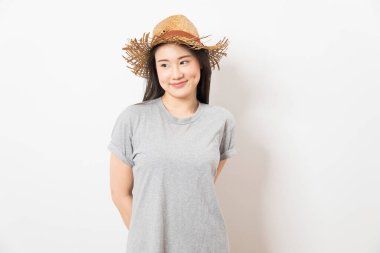 Beyaz arka planda duran gri tişörtlü ve hasır şapkalı Asyalı kız..