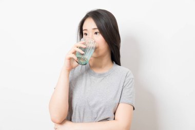 Güzel genç Asyalı kadın bir bardak su minerali içiyor, evinde mutlu..